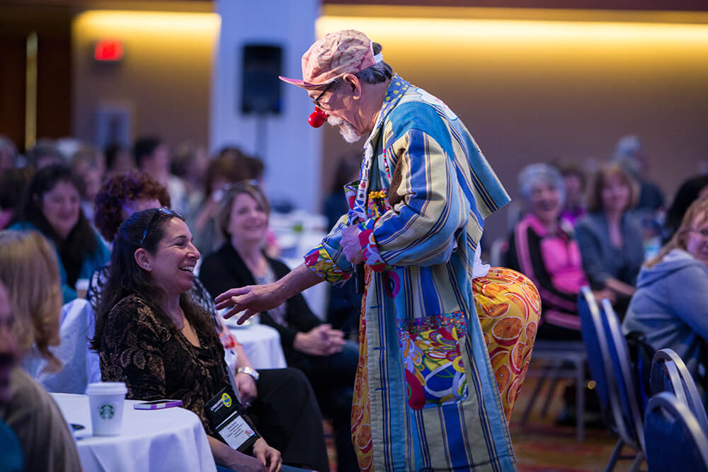 A man in a silly costume interacts with attendees at a conference