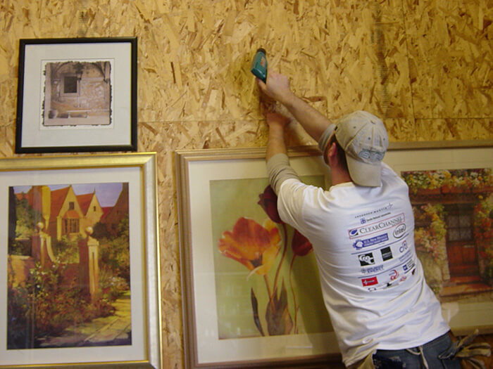 A man hangs framed artwork for Make a Difference Day