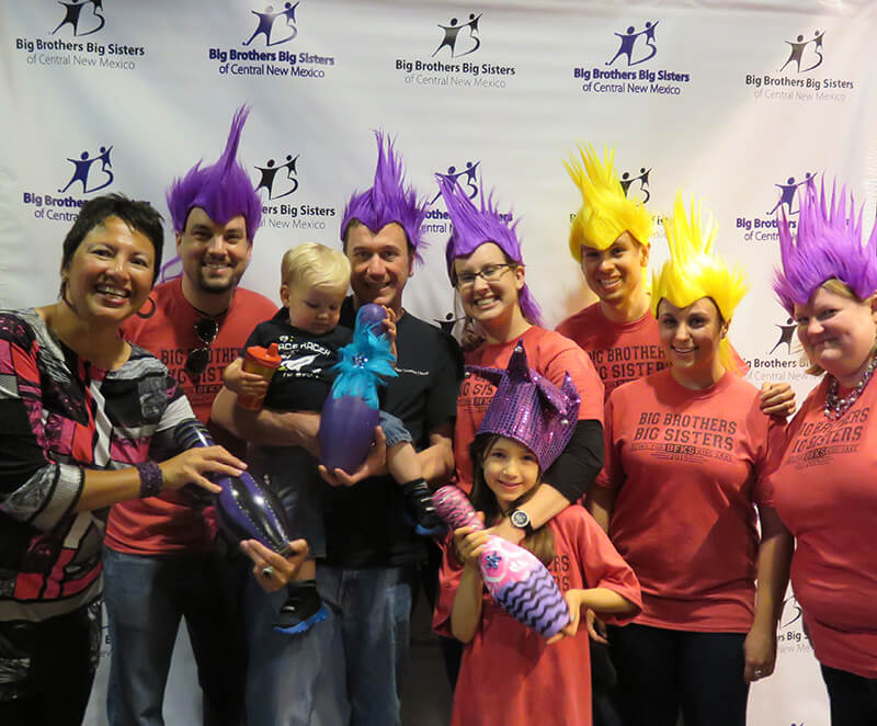 Big Brothers and Big Sisters give back to the community, wearing funny wigs and pose for a group picture