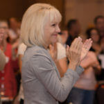 Leann claps and smiles, impressed with the professionalism of the conference